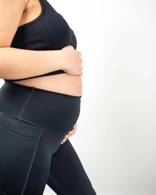 Pregnant woman holding belly in black gymwear 
