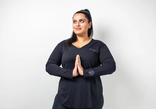 British Indian woman sat down in PADA black gymwear 